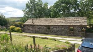 a small brick house with a car parked in front of it at Gibraltar Farm Cottage in Hebden Bridge