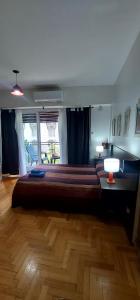 1 dormitorio con 1 cama grande y suelo de madera en Cómodo departamento con balcón en Microcentro en Buenos Aires