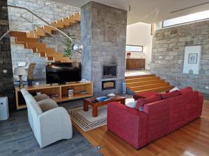 a living room with two red couches and a stone wall at São Vicente Lodge - Panoramic Retreat in Capelas