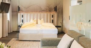 1 dormitorio con cama blanca y sofá en Forster's Naturresort en Neustift im Stubaital