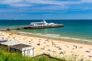 a beach with a pier and a crowd of people at Coastal Vibes - Stunning Bournemouth Apartment with King Size Bed and Free Parking - Central Location and Close to Beach in Bournemouth