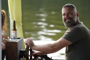 a man standing on a boat with a bottle of wine at Floss Priepert 2 in Priepert