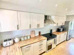 a kitchen with white cabinets and a stove top oven at Greenacre Lodge - cosy, dog-friendly rural home with private garden in Redgrave