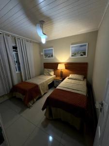 ein Hotelzimmer mit 2 Betten und einer Lampe in der Unterkunft Casa com Piscina ao lado do Shopping in Cabo Frio