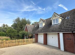 a red brick house with a white garage at Greenacre Lodge - cosy, dog-friendly rural home with private garden in Redgrave