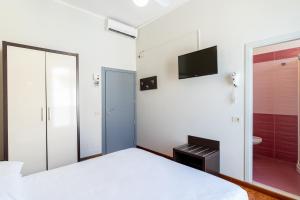 チェゼナーティコにあるAmare Beach Hotelのベッドルーム(白いベッド1台、テレビ付)