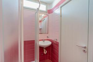 un bagno rosa con lavandino e doccia di Amare Beach Hotel a Cesenatico