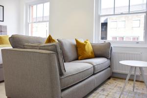 un sofá gris con almohadas amarillas en la sala de estar. en Luxury Harley Street Apartments, en Londres