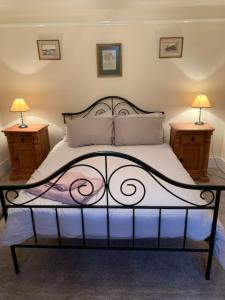 a bedroom with a bed with two nightstands and two lamps at Vinny Cottage in Owermoigne