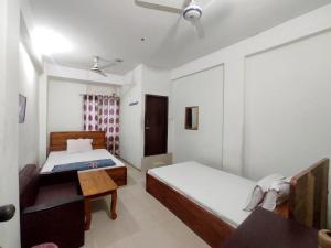 a bedroom with two beds and a ceiling fan at New Hotel Labbaik in Dhaka