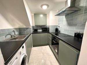 a small kitchen with a sink and a dishwasher at Chic 2-Bed Flat Private Garden SE13 in London