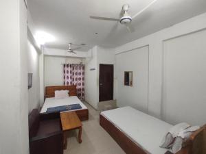 a bedroom with two beds and a ceiling fan at New Hotel Labbaik in Dhaka