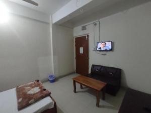 a room with a bed and a table and a tv at New Hotel Labbaik in Dhaka