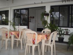 a table with white chairs and a table and some plants at Pousada Convento Da Penha in Vila Velha