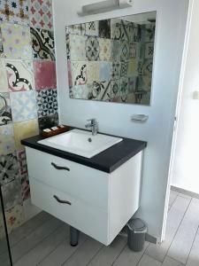ein Badezimmer mit einem weißen Waschbecken und einem Spiegel in der Unterkunft Le Orlika in Grand-Bourg