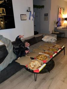 Ein Mann, der auf einer Couch mit Kisten Pizza liegt. in der Unterkunft Ofek's place - Midtown TLV in Tel Aviv