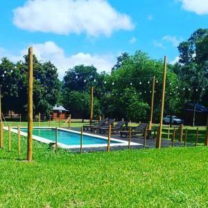 una piscina en un parque con bancos y césped en Cabañas El Despertar en Puerto Iguazú