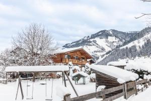 a log cabin in the snow with mountains in the background at Apartment Gästehaus Luggau in Rauris