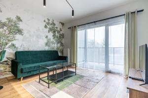 a living room with a green couch and large windows at Ceglana Green Studio in Katowice