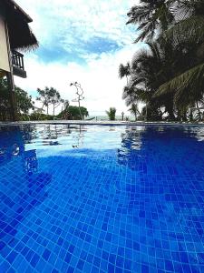 a blue swimming pool with palm trees in the background at Blue Ocean Resort in Netolpitiya