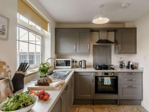 a kitchen with gray cabinets and a counter top with vegetables at 2 Bed in Winterton-on-Sea 85872 in Winterton-on-Sea