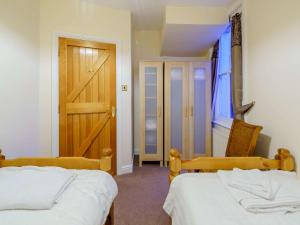 a bedroom with two beds and a wooden door at 2 Bed in Keswick 86100 in Keswick