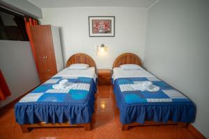 twee bedden in een kleine kamer met blauw en wit bij Hotel Mayros in Satipo
