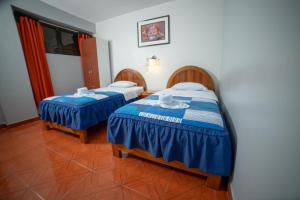 - 2 lits dans une chambre avec des draps bleus et blancs dans l'établissement Hotel Mayros, à Satipo