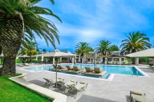 a pool with chaise lounge chairs and umbrellas at Iris Hotel in Siviri