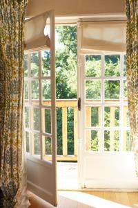 an open window in a room with a curtain at Cazaudehore, hôtel de charme au vert in Saint-Germain-en-Laye