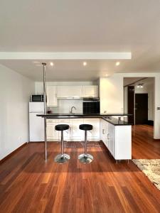 een lege keuken met twee barkrukken erin bij L'ATHOS - Appartement équipé - Entre Paris et Versailles - Haut débit in Garches