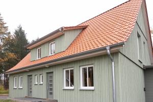 a green house with an orange roof at Ferienwohnungen in Wald und Flur - Wohnung Flur in Lüder