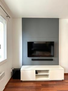een witte woonkamer met een flatscreen-tv aan de muur bij L'ATHOS - Appartement équipé - Entre Paris et Versailles - Haut débit in Garches