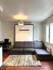 een woonkamer met een bank en een tafel bij L'ATHOS - Appartement équipé - Entre Paris et Versailles - Haut débit in Garches