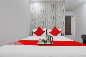 Habitación de hotel con cama con almohadas rojas en Super OYO Alwal Residency, en Hyderabad