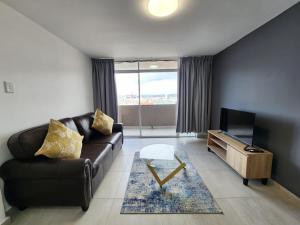 sala de estar con sofá de cuero y TV en Penzance - Beach Accommodation, en Durban