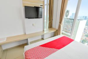 um quarto com uma cama e uma janela com uma televisão em OYO 93432 Tree Room Hotel em Kebonnanas