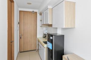 uma cozinha com um frigorífico preto e armários de madeira em OYO 93432 Tree Room Hotel em Kebonnanas
