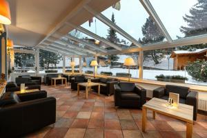 ein Restaurant mit Sofas, Tischen und Fenstern in der Unterkunft Piccolo Hotel in Wolkenstein in Gröden