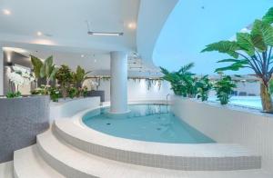 a large swimming pool in a building with palm trees at Hanza Tower 2BDR with Sauna & Jacuzzi & Pool in Szczecin