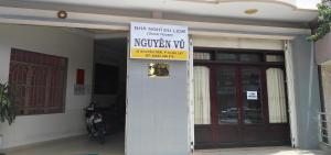 a sign on the front of a building with a motorcycle parked outside at Nhà Nghỉ Du Lịch Nguyên Vũ in Da Lat