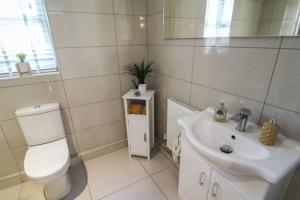 a white bathroom with a toilet and a sink at Izzy's house in Deysbrook