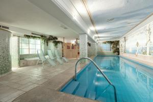 a swimming pool with blue chairs and a swimming pool at Piccolo Hotel in Selva di Val Gardena