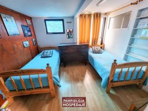 a bedroom with two twin beds and a dresser at Hostal Pampaloja in Antofagasta