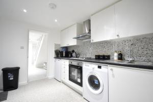 una cucina bianca con lavatrice e lavandino di Superb Garden Apartment a Londra