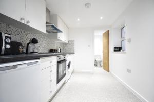 una cocina blanca con armarios y electrodomésticos blancos en Superb Garden Apartment en Londres