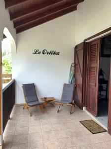 2 Stühle auf einer Veranda mit Schild an der Wand in der Unterkunft Le Orlika in Grand-Bourg