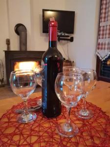 een fles wijn en vier wijnglazen op een tafel bij Vikendica Cican Jahorina in Jahorina