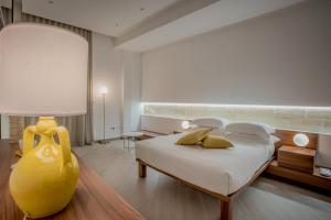 a bedroom with a large bed and a yellow vase at Tufo Bianco Relais in Massafra
