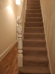 a stairway with a brown carpet and a stair case at Whites Place in Slades Green